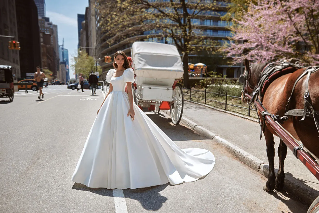 Gorgeous dress for a princess wedding look. The lush gown is made of glossy fabric and has no additional decorations. The corset is embellished with delicate Boat neckline and elbow-length loose sleeves with take-ups in the shoulders zone. - Image 3