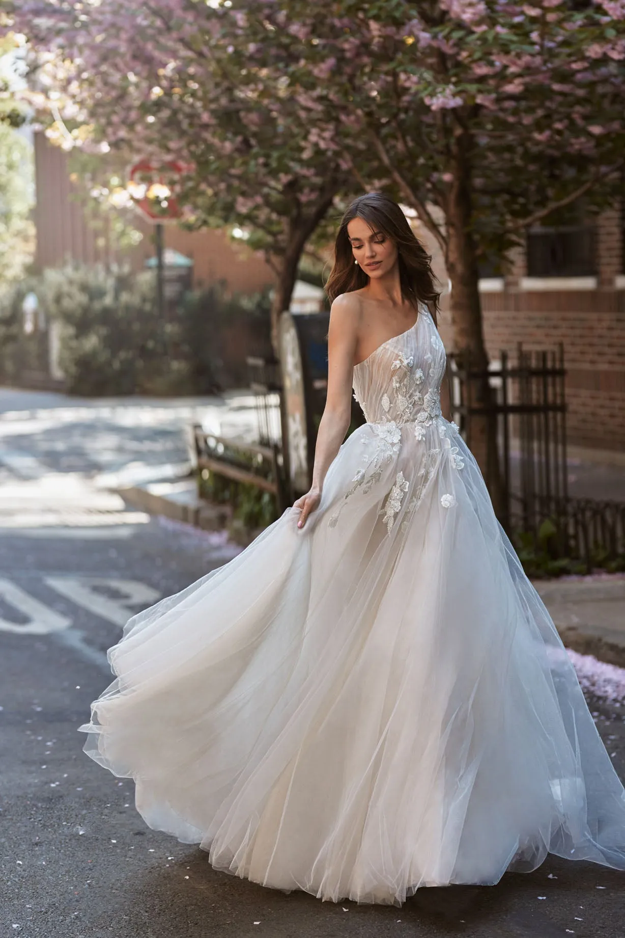 Expremely feminine and fragile wedding gown. The top is embellished with the scrunched up Tulle and floral elements that cover one shoulder. The skirt is made of numerous layers of Tulle with accentuated waistline and 3D floral lace. - Image 3